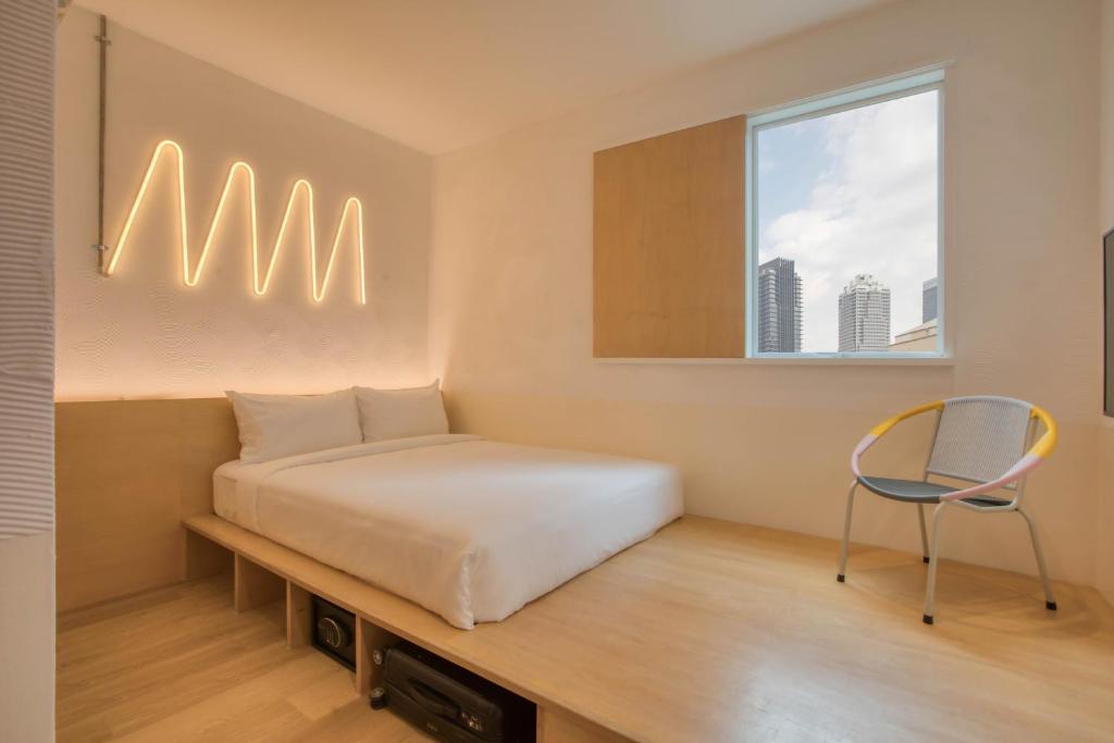 吉隆坡MoMo's Kuala Lumpur的一间卧室配有一张床和一把椅子