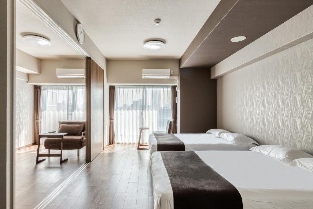 大阪斯选・新大阪酒店公寓的酒店客房,配有两张床和椅子