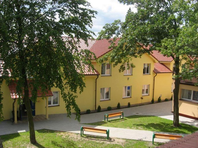 韦巴Ośrodek Wczasowo - Kolonijny Słoneczko的黄色建筑前的两长椅