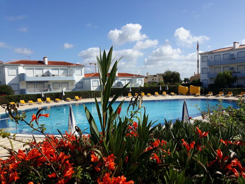 波尔蒂芒Apartment Palmeiras的一座带椅子和鲜花的游泳池,位于一座建筑前