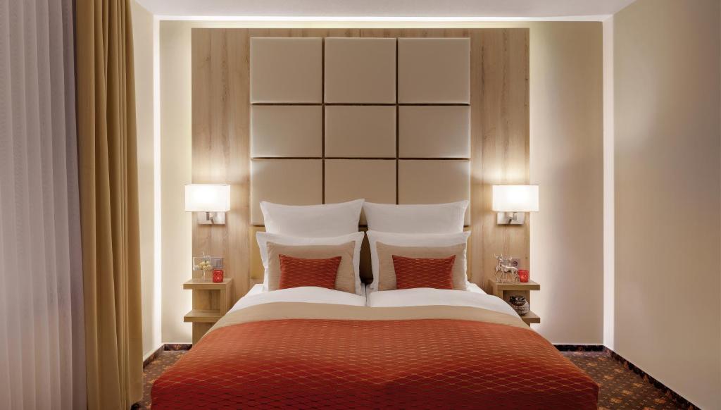 汉诺威Hotel Wegner - T h e culinary art hotel的一间卧室配有一张大床和两盏灯
