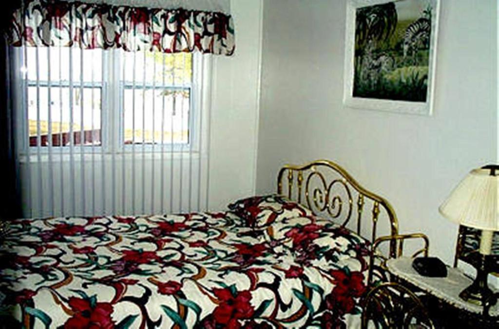 Johnstown约翰斯敦汽车旅馆的一间卧室配有一张带鲜花毯子的床和窗户。