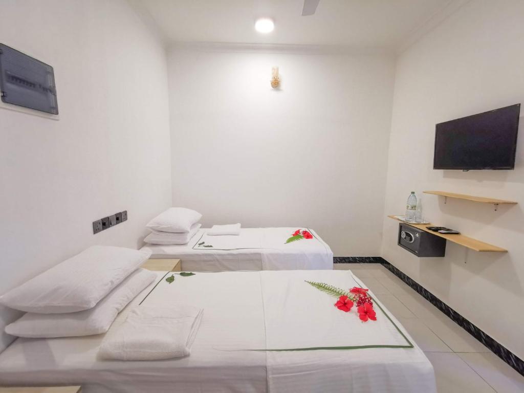 图杜Sky Inn Thoddoo的一间医院间 - 带两张床和一台平面电视