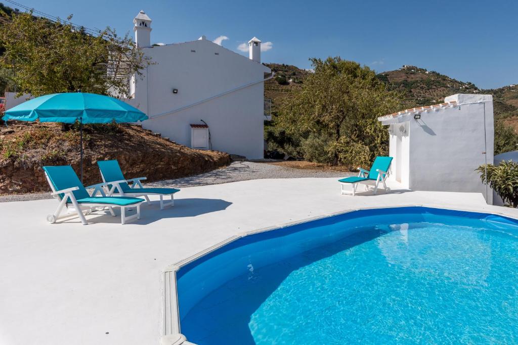 赛阿隆加Villa Felicidad destino romántico的房屋旁的游泳池配有椅子和遮阳伞