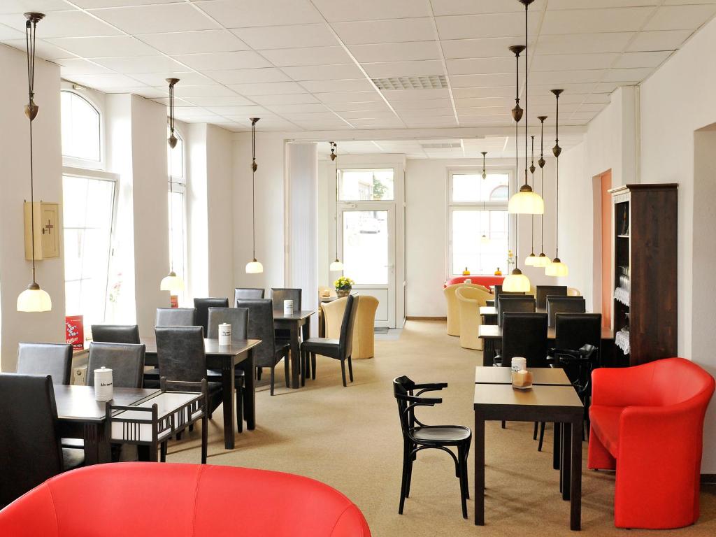 赖兴巴伊姆福格特兰米勒斯阿尔特巴克斯图膳食公寓酒店的餐厅设有黑色桌子和红色椅子