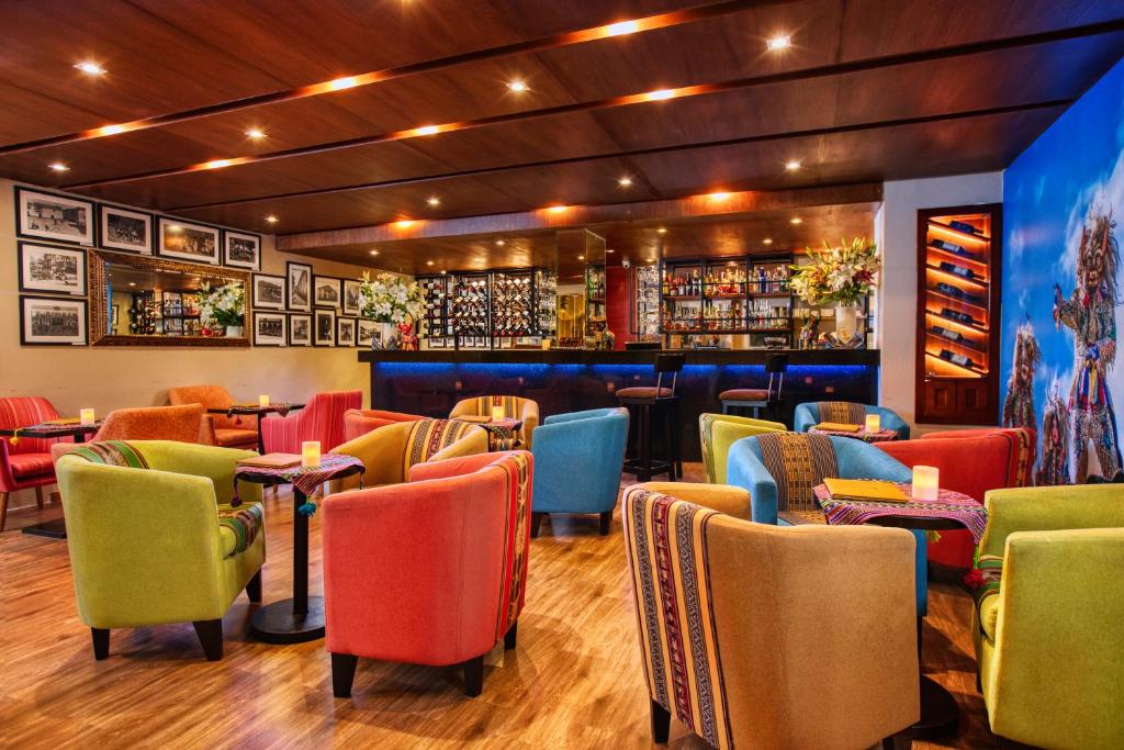 库斯科Xima Exclusive Cusco的一间设有五颜六色椅子的餐厅和一间酒吧