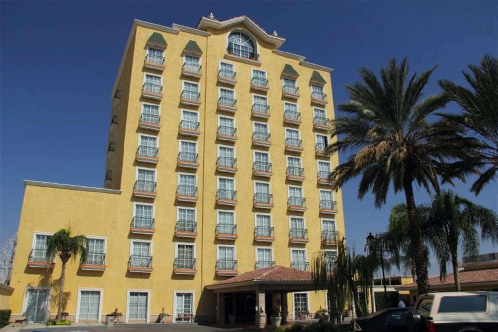 托雷翁波萨达德尔里奥贝斯特韦斯特快捷酒店的一座黄色的大建筑,前面有棕榈树
