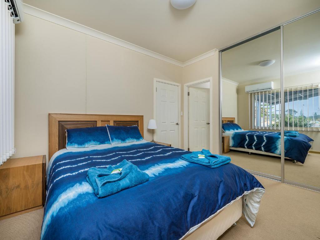 朱里恩湾海滨50号别墅的一间卧室配有一张蓝色大床和镜子