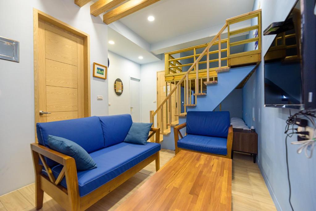 马公夏海民宿的客厅设有蓝色的沙发和楼梯。