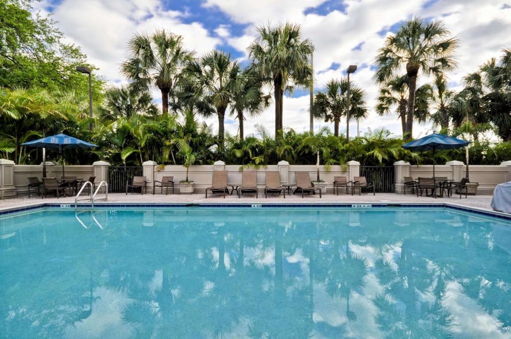 坦帕Hyatt Place Tampa Airport/Westshore的一个带椅子和棕榈树的大型游泳池