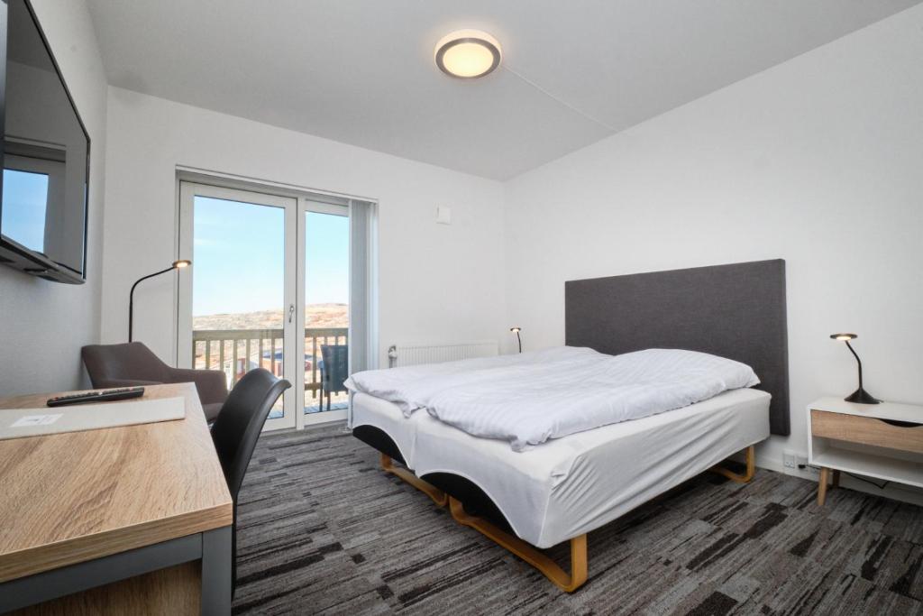 伊卢利萨特艾斯菲尔得公寓酒店的白色的卧室设有床、书桌和窗户