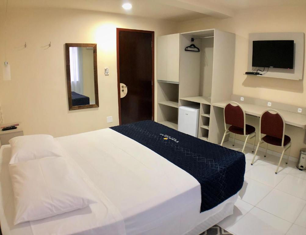 库里提巴特拉萨斯酒店的一间卧室配有一张床、一张书桌和一台电视