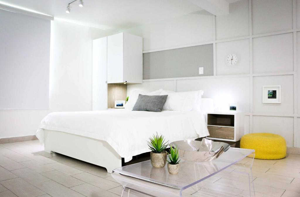 圣胡安Avila Guesthouse的白色的卧室配有白色的床和一张桌子