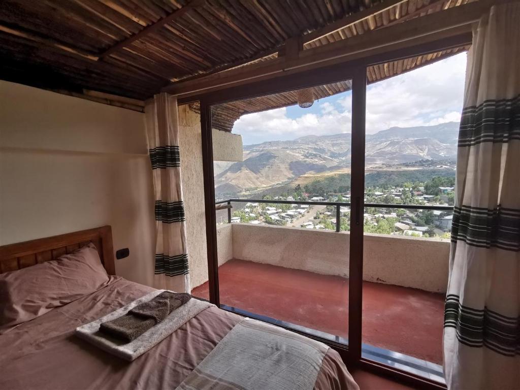 拉利贝拉Lalibela Apartments的一间卧室设有一张床和一个大窗户