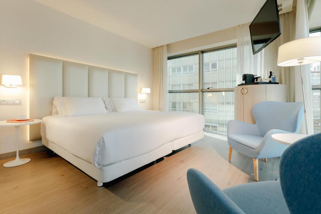 拉科鲁尼亚Hesperia A Coruña Centro的卧室配有一张白色大床和一把椅子