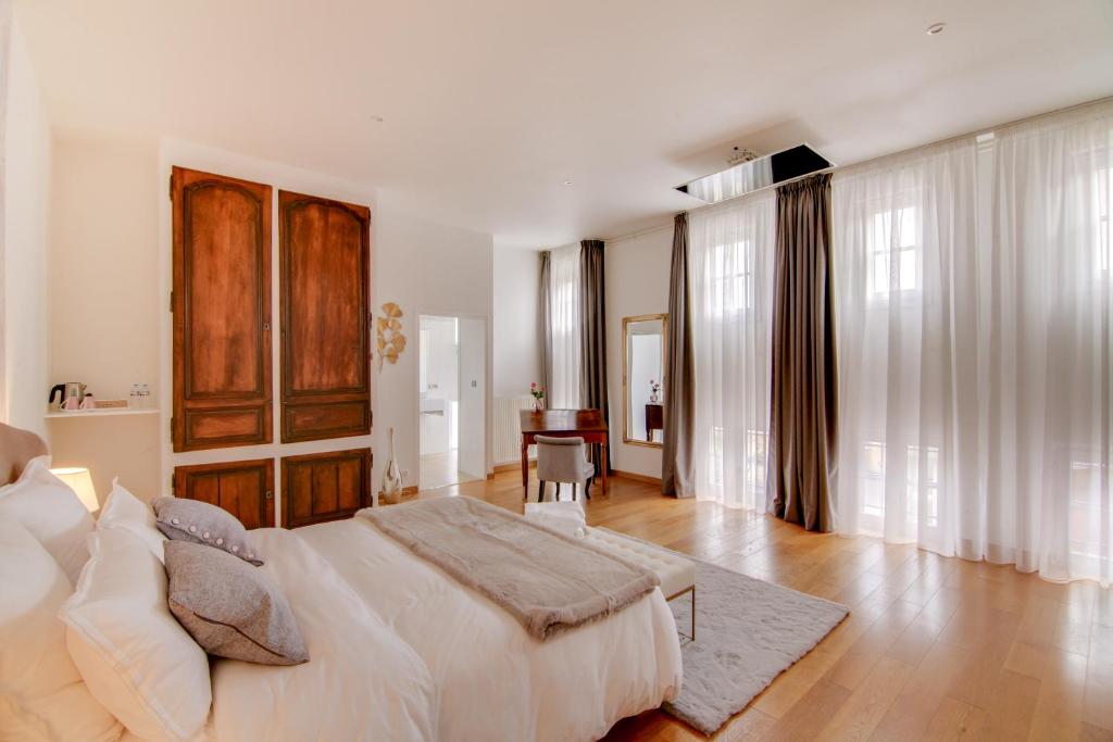 巴勒迪克Maison d'hôtes La Villa des Ducs Bar-le-Duc的白色卧室配有一张大床和一张桌子