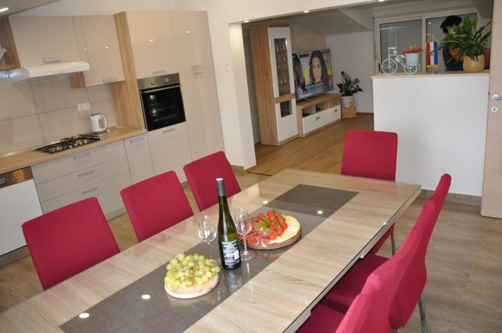 斯普利特Apartman Đoni的餐桌、红椅子和一瓶葡萄酒