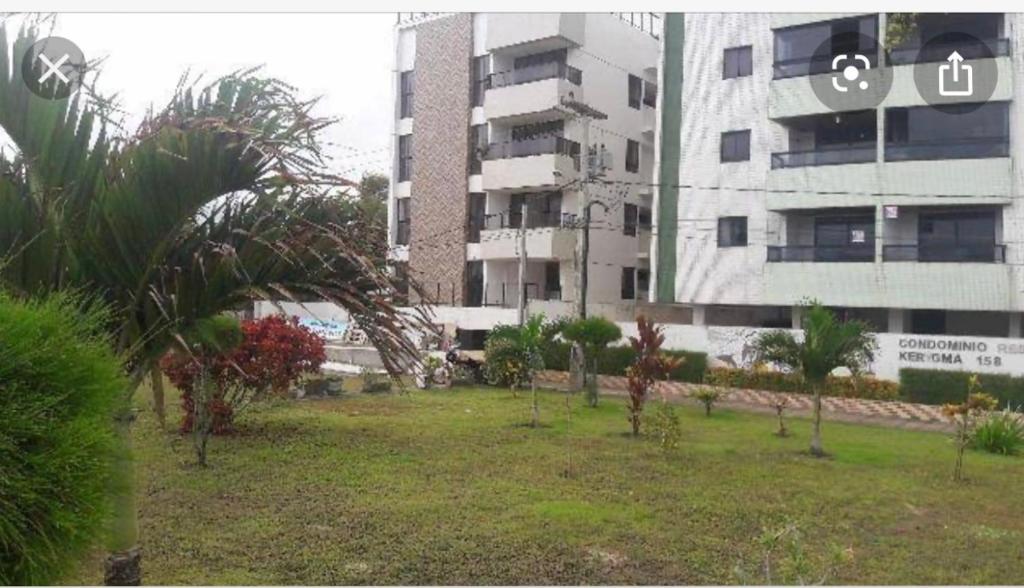 卡贝德卢Apartamento beira mar Intermares roupas de cama e AR CONDICIONADO COBRADO À PARTE的一座树木繁茂的建筑前的公园