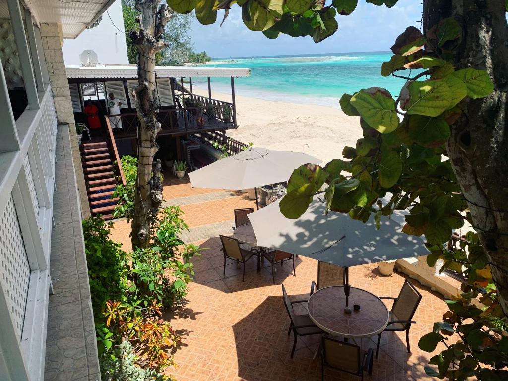 布里奇敦Beach Vue Barbados的一个带桌椅的庭院和海滩