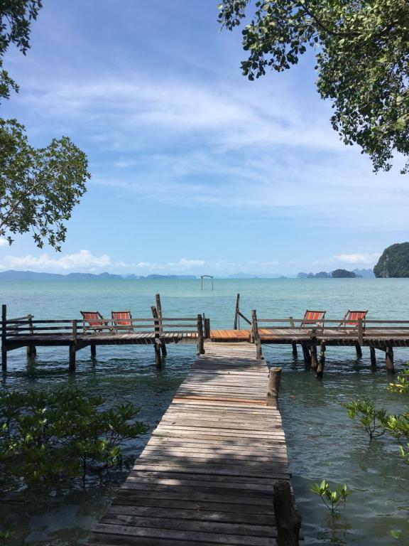 Tha Lane Bay香蕉度假酒店及餐厅的一个带椅子的木制甲板,位于水面上
