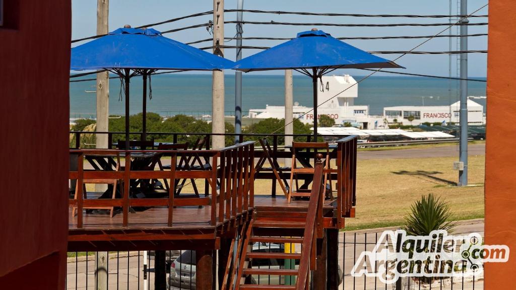 马德普拉塔Vista al Mar Punta Mogotes的甲板上一张桌子和两把蓝色遮阳伞