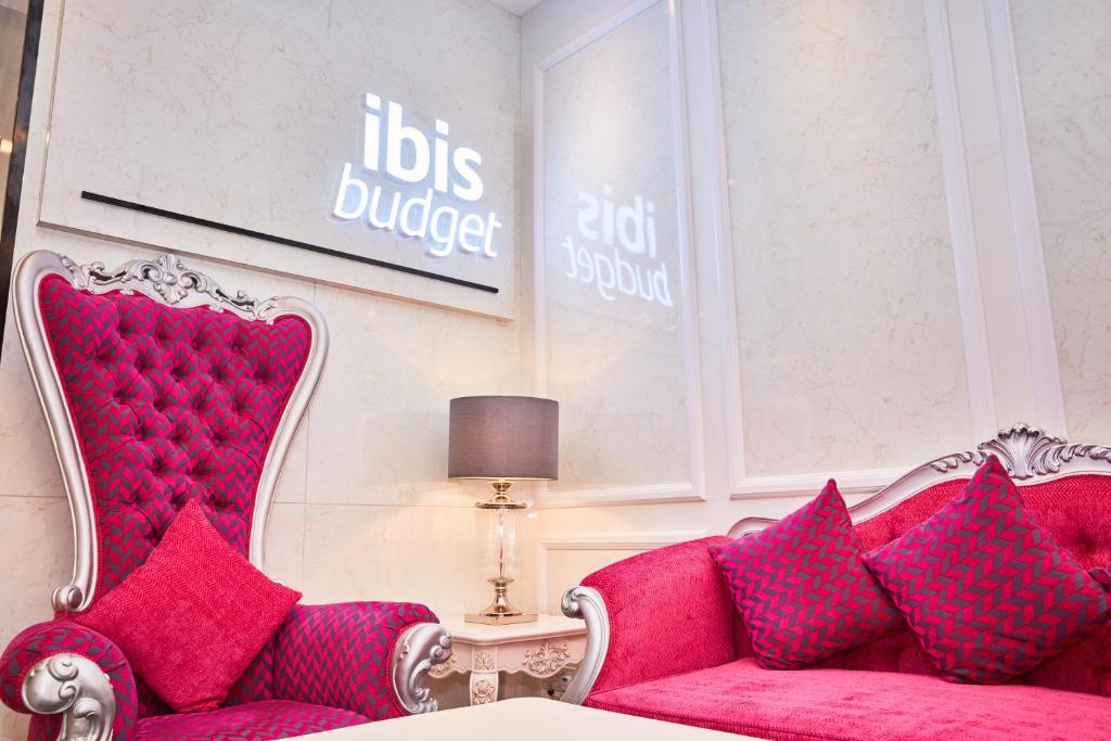 新加坡ibis budget Singapore Joo Chiat的客厅配有红色沙发及粉红色枕头