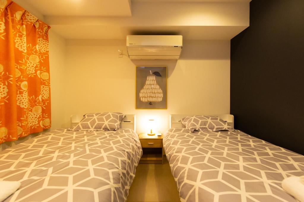 东京Cross Bridge Ikebukuro的一间卧室配有两张床和一盏灯。