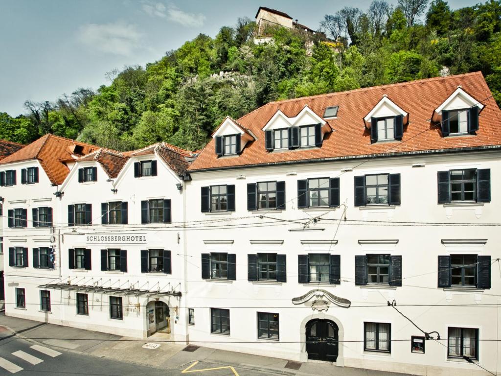 格拉茨Schlossberghotel的一座白色的大建筑,有红色的屋顶