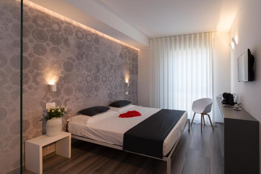 马帝斯兹罗Hotel Mediterraneo -Spiaggia Ombrelloni e Lettini Inclusi-的卧室配有1张床、1张桌子和1把椅子
