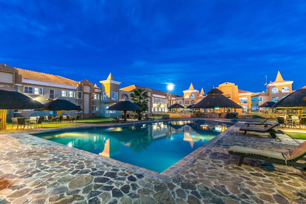 帕拉佩Majestic Five Hotel的度假村的游泳池配有桌子和遮阳伞