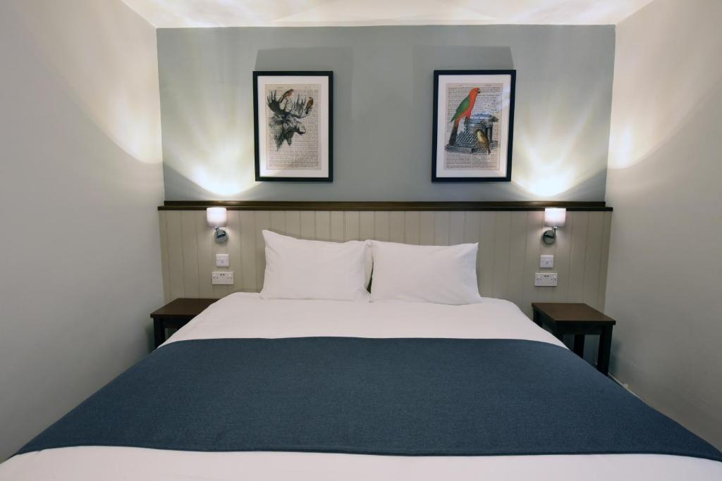 切斯特Oaklands by Greene King Inns的卧室配有一张带两张桌子的大型白色床