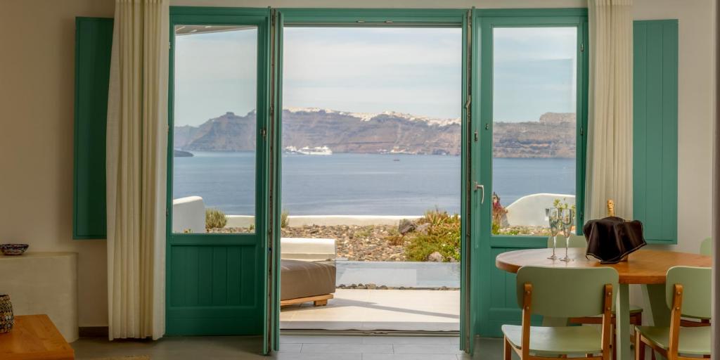 阿克罗蒂里海王星豪华套房酒店的客房设有绿色门和一张桌子,享有海景。