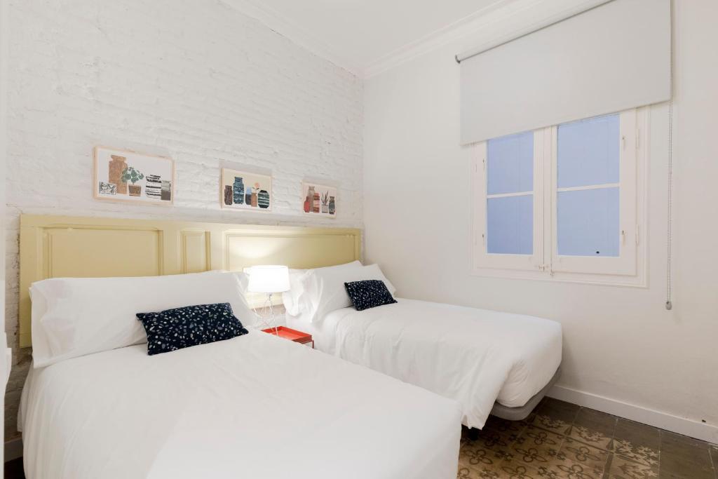 巴塞罗那Aspasios Gracia Apartments的配有2张床的白色墙壁和窗户客房