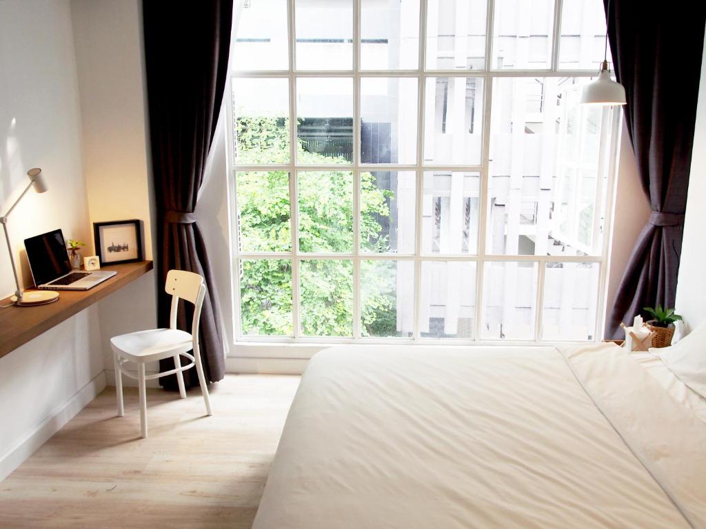 曼谷瓦姆泰尔酒店的一间卧室设有一张床和一个大窗户