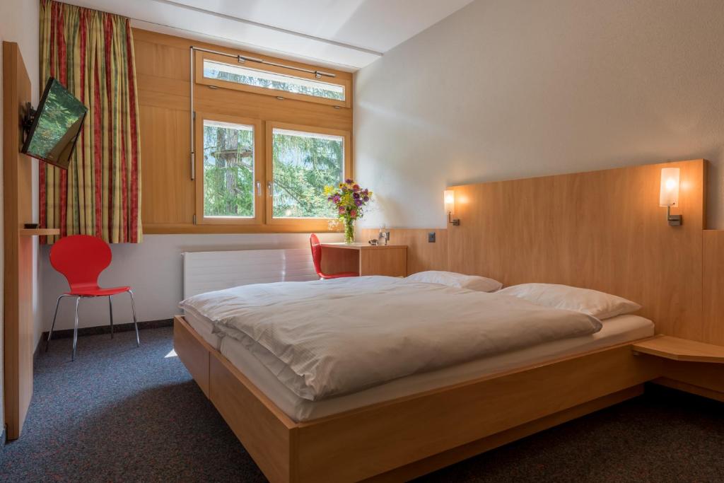 菲施Sport Resort Fiesch, Garni Aletsch的一间卧室配有一张大床和一张红色椅子
