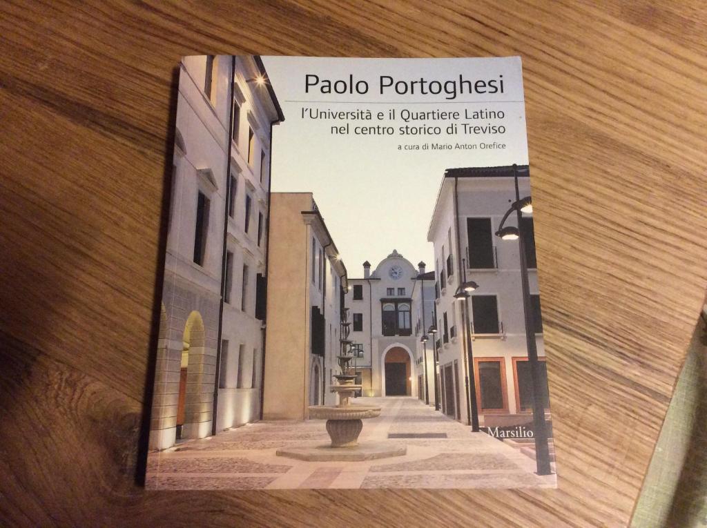 特雷维索圣莱昂纳多拉蒂娜套房公寓的一张桌子上的书,上面有街道的照片