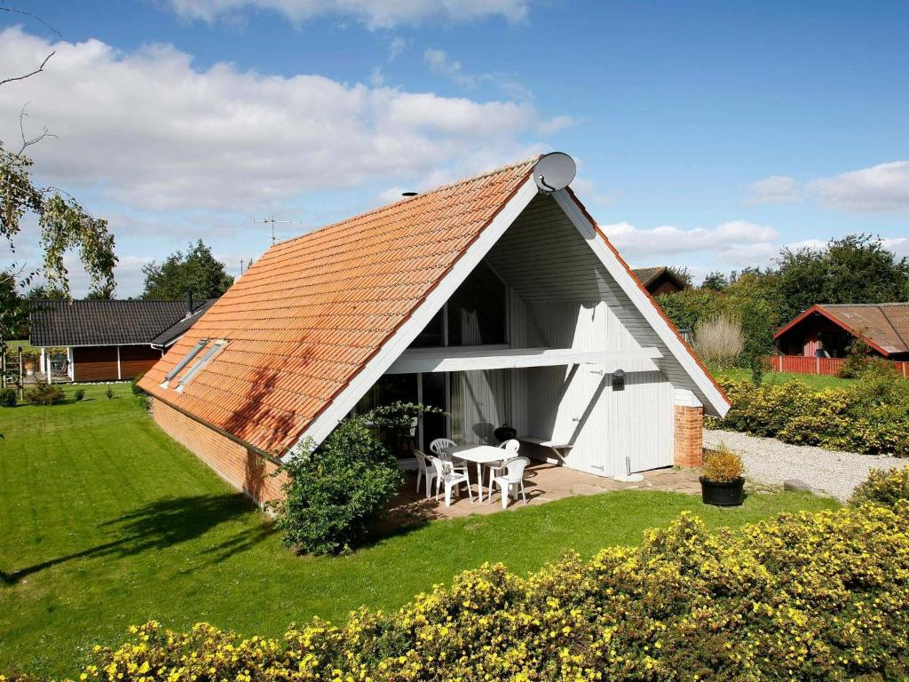 森讷比Five-Bedroom Holiday home in Juelsminde 2的庭院中白色小屋,屋顶橙色