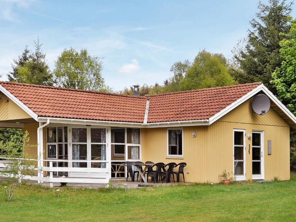 EngesvangThree-Bedroom Holiday home in Silkeborg 7的黄色的房子,配有椅子和桌子