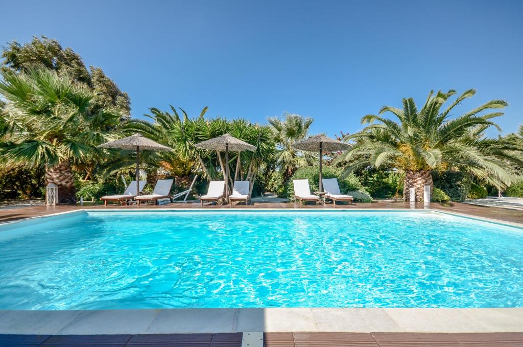 布拉卡Valena Mare Suites & Apartments的一个带椅子的游泳池,棕榈树