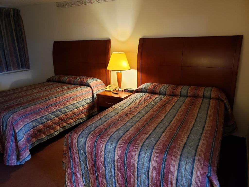 亨丁顿亨廷登汽车旅馆的酒店客房设有两张床和一张桌子上的台灯。