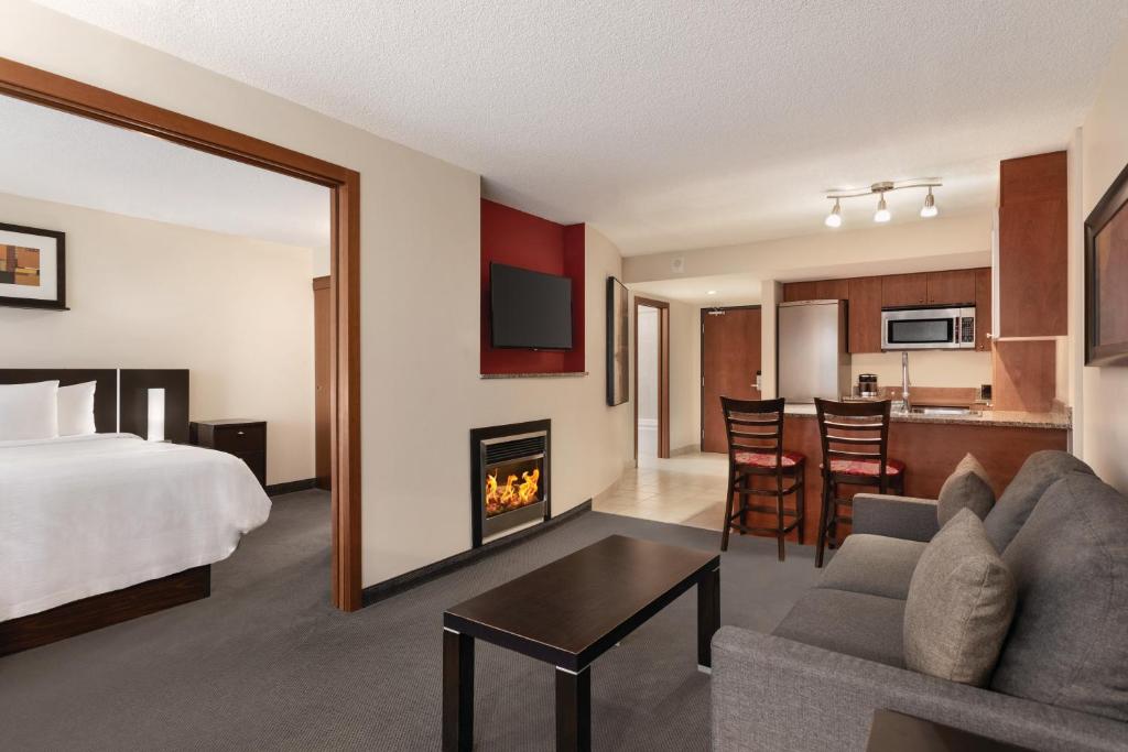 蒙特利尔蒙特利尔希尔顿合博套房酒店的一间卧室设有一张床,客厅设有壁炉。