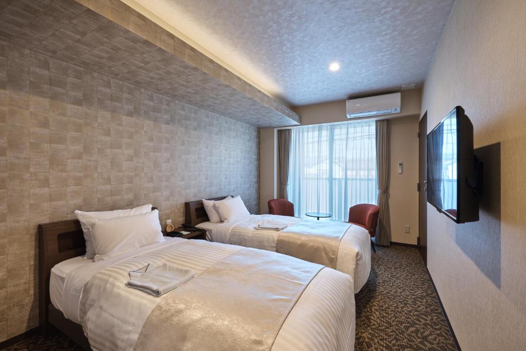 京都HOTEL ARROWS ARASHIYAMA的酒店客房设有两张床和电视。