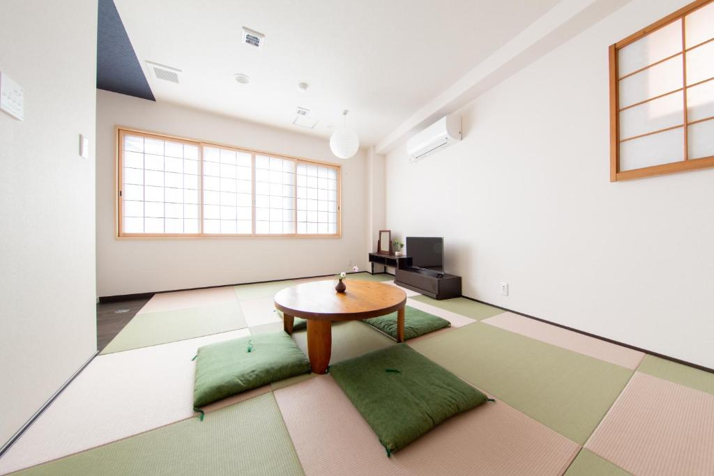 大阪Yado Hachiemon的一间设有桌子和绿色靠垫的客房