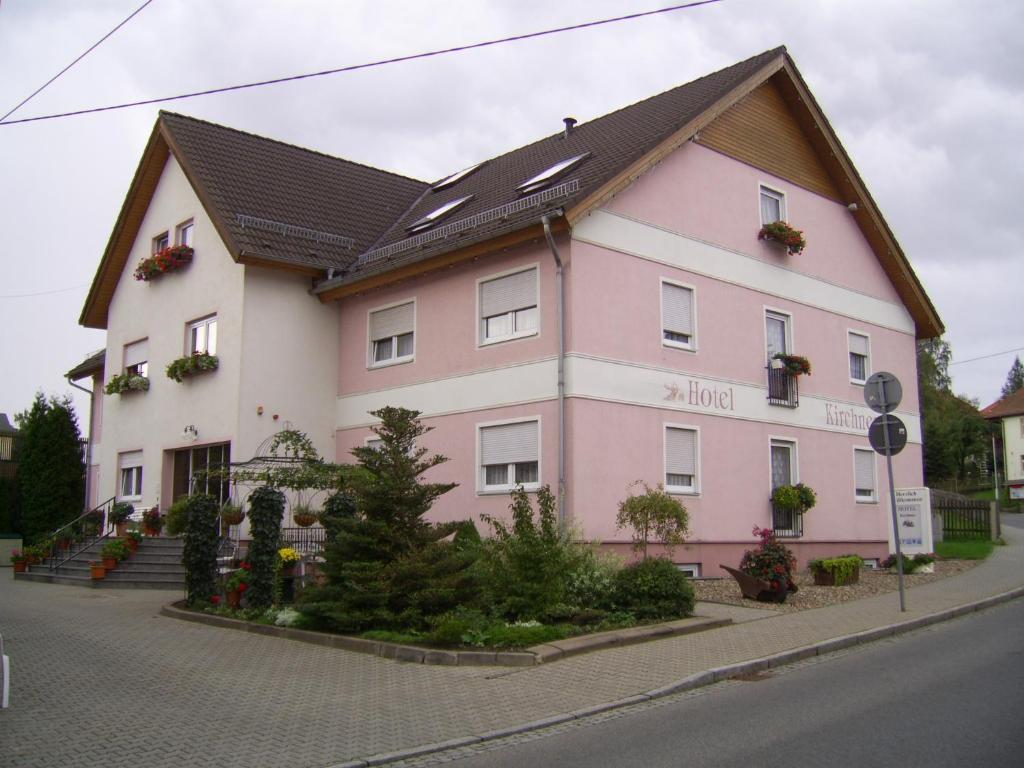 萨兰德特基什内尔酒店的街道边的粉红色和白色建筑