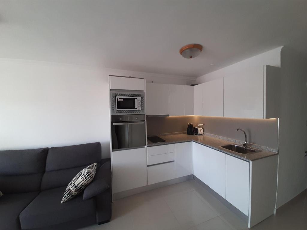 英格兰海滩普拉亚公寓的厨房配有白色橱柜和沙发
