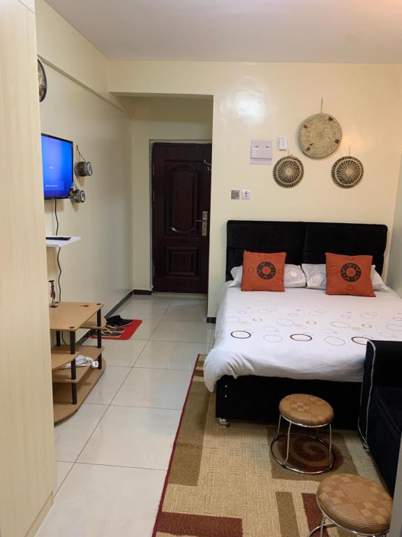 内罗毕Ruthys Apartment的一间卧室配有带橙色枕头的床和电视。