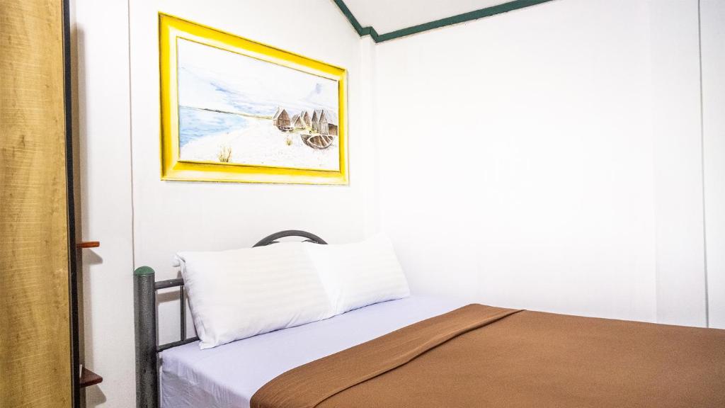 卡马拉海滩萨比那客栈的卧室配有一张床,墙上挂着一幅画