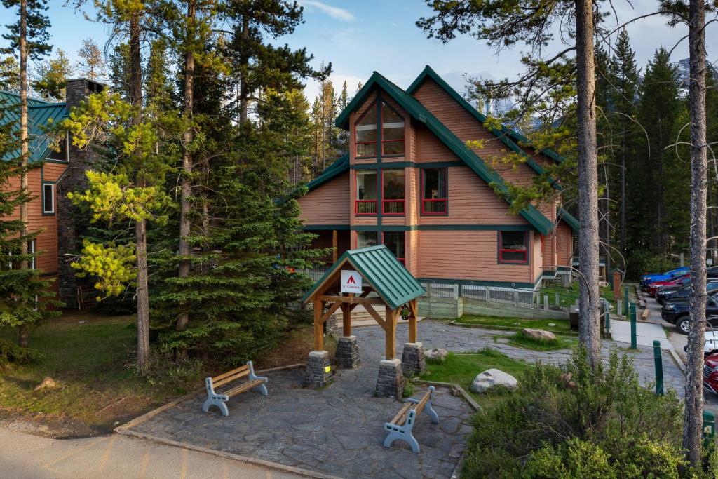 路易斯湖HI Lake Louise Alpine Centre - Hostel的树林中的房屋,前面有长椅