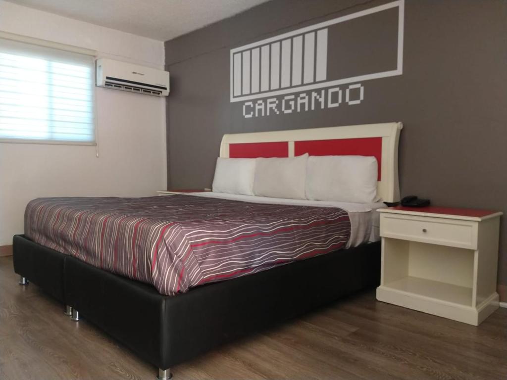 墨西卡利Hotel Boulevard Mexicali的一间卧室配有一张大床和红色床头板