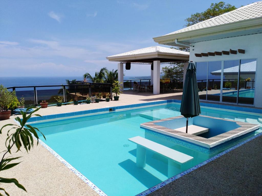 达拉盖地Seaview Mansion Dalaguete - Apartment 5的一座房子旁带遮阳伞的游泳池